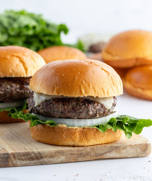 A group of wagyu hamburgers on brioche buns, dressed with cheese, lettuce and onions