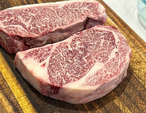 2 highly marbled wagyu ribeyes on a cutting board