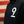 Close-up of a black hoodie with a large white number 9 printed on the chest, worn by a person in front of a blurred red and beige striped background.