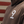 A close-up of a person wearing a brown hoodie with a large white number 9 printed on the chest, set against a background of red and beige horizontal wooden planks.