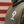 Close-up of a person wearing an olive green hoodie with a large white number 9 printed on the chest, set against a red and white striped wooden background.