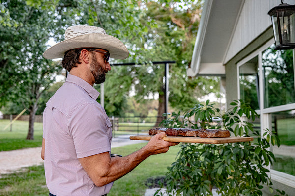 Owner Wes Madden carrying a cutting board of steaks into the house